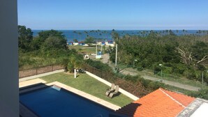 A view of a swimming pool with a clear blue sky and the ocean in the background. - Spectacular Ocean View  Penthouse, Terrace, 2br, 2bth -  Surrounded by Nature (Cabo Rojo)