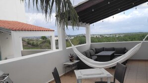 A rooftop terrace with a hammock, outdoor seating, a table, and chairs. - Spectacular Ocean View  Penthouse, Terrace, 2br, 2bth -  Surrounded by Nature (Cabo Rojo)