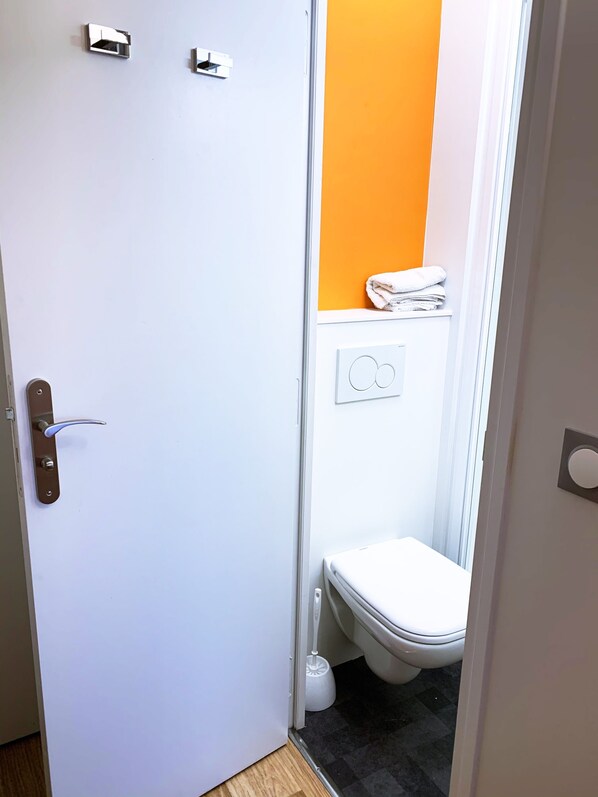 A small bathroom with a toilet, a hand dryer, and a towel rack. - Premiere Classe Paris Nord - Sarcelles (Sarcelles)