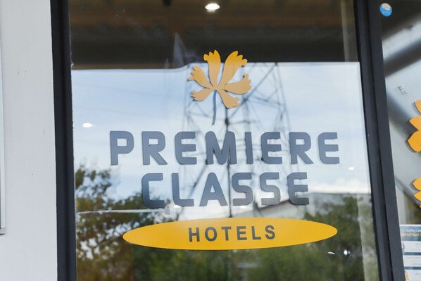 Una ventana con el texto "PREMIERE CLASSE HOTELS" y un logo de hoja de arce.