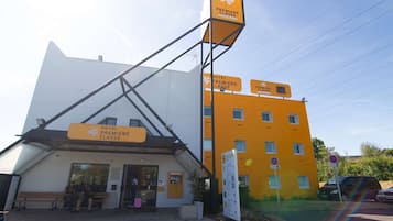 Un hotel con una entrada destacada, asientos al aire libre y un letrero que indica un descuento del 60%.