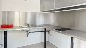 Een moderne keuken met roestvrijstalen werkbladen, een gootsteen en een rode gereedschapskist.