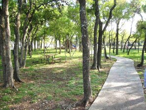 Un parque con un sendero pavimentado, bancos y árboles.