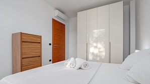A bedroom with a bed, a wooden wardrobe, and a white wardrobe. - Holiday Apartment "Villa Marconi 5" with Sea View, Covered Terrace & Large Garden (Golfo Aranci)