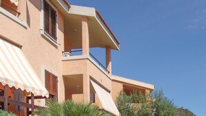 A multi-story building with balconies, a striped awning, and a clear blue sky.