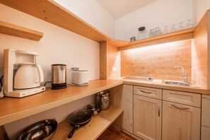 A compact kitchen with wooden cabinets, a countertop, a coffee maker, a toaster, and a sink.