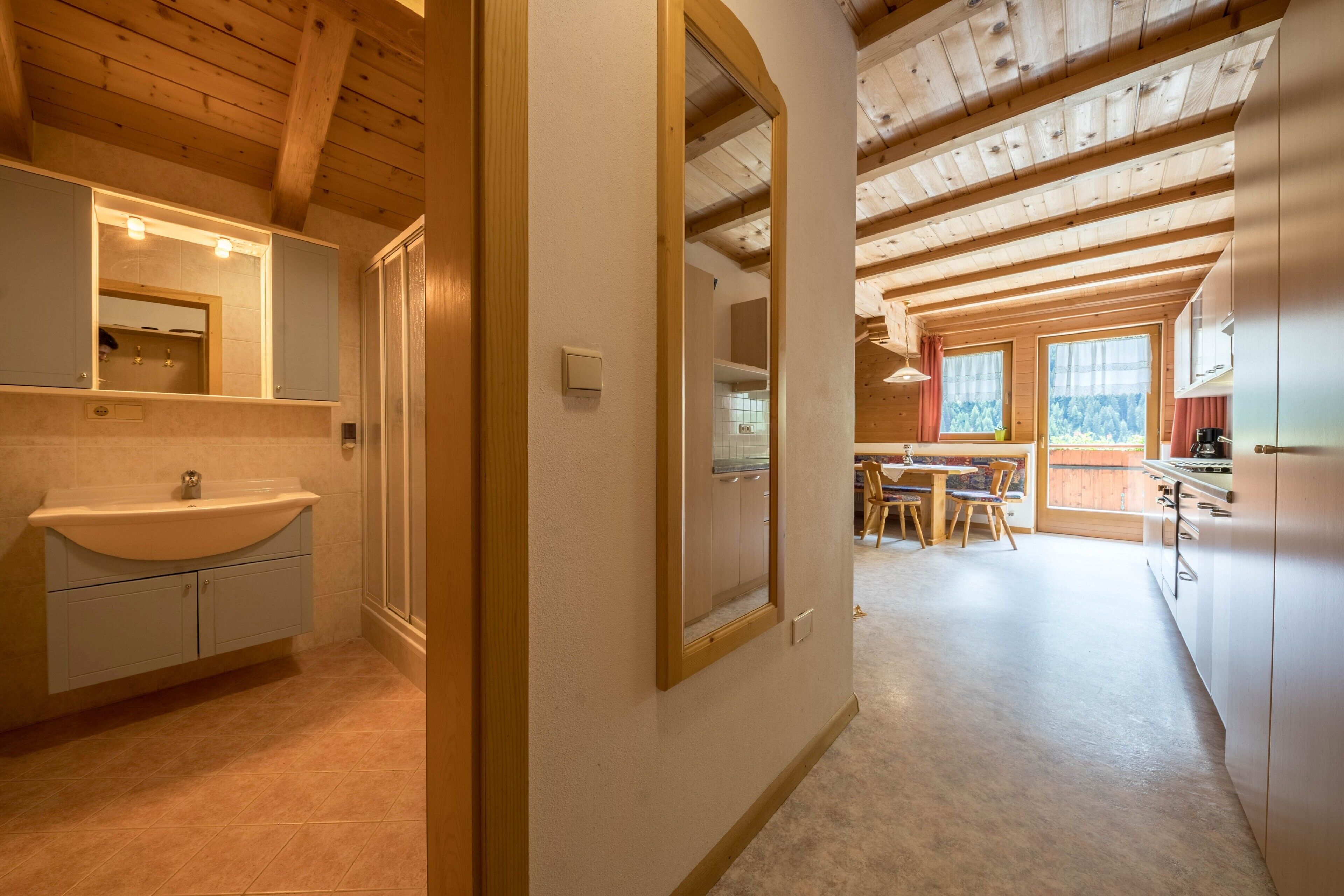 A wooden interior with a bathroom, a dining area, and a kitchen.