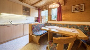 A wooden interior with a kitchen, bench seating, and a table with a lace table runner. - Cozy Apartment "Haus Hubertus - 6" with Mountain View & Wi-Fi (Walten)