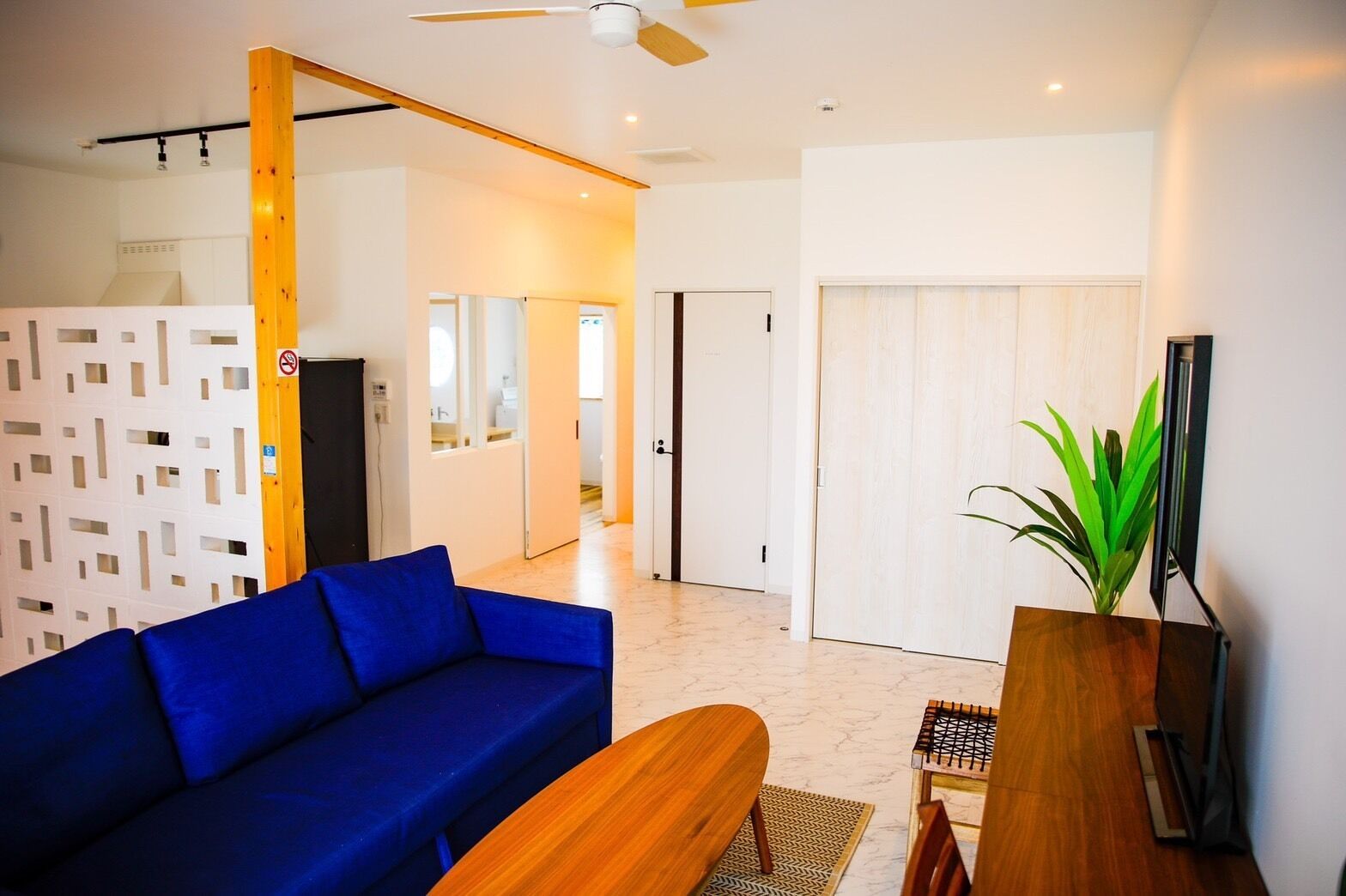A modern living room with a blue sofa, wooden coffee table, and a potted plant.