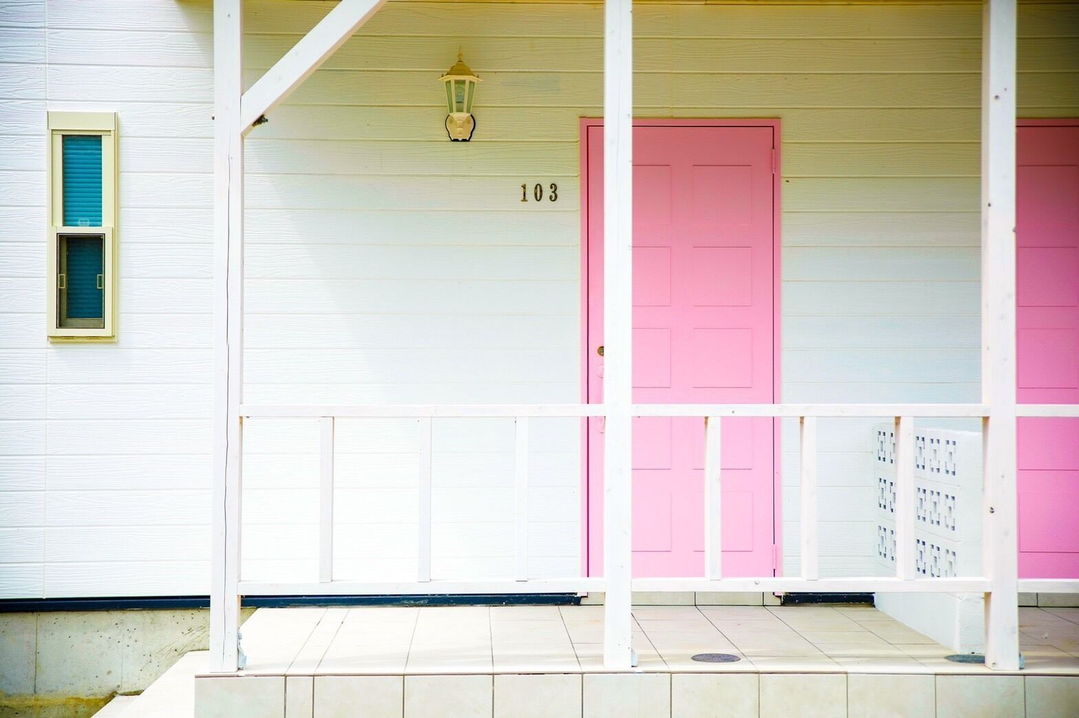 A white building with a pink door and a number '103' above it.