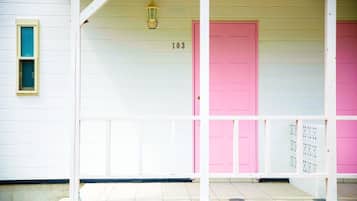 A white building with a pink door and a number '103' above it.