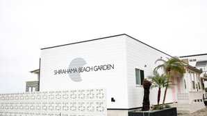 A white building with the sign "SHIRAHAMA BEACH GARDEN" and a palm tree in front. - Shirahama Beach Garden (Miyazaki)