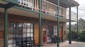 Un immeuble de deux étages doté d’un balcon, de murs en briques et de grandes fenêtres.