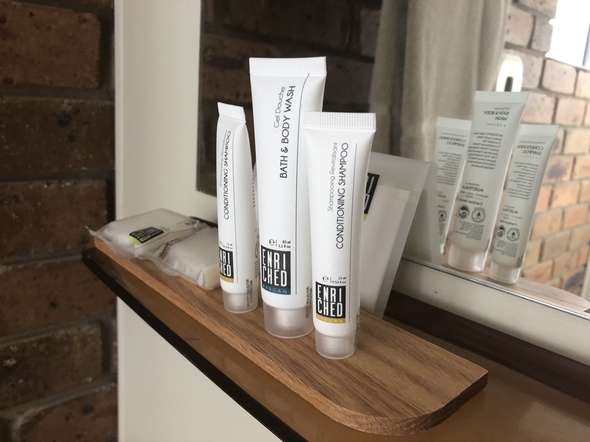 Three tubes of ENRICHED body wash on a wooden shelf.