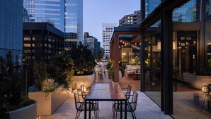 A rooftop patio with outdoor seating, a view of the cityscape, and modern buildings. - Little National Hotel Sydney (Sydney)
