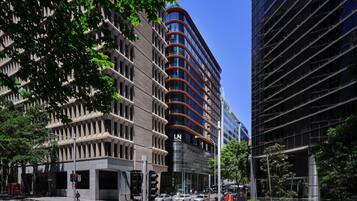A modern hotel with a curved facade, large windows, and a prominent 'L' logo.