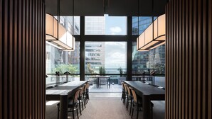 A modern meeting room with large windows, a conference table, and chairs. - Little National Hotel Sydney (Sydney)