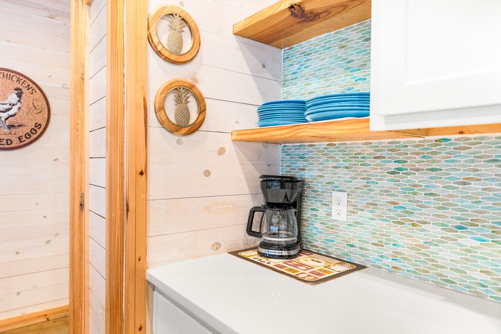 A kitchen with wooden cabinets, a coffee maker on the counter, and a tiled backsplash.