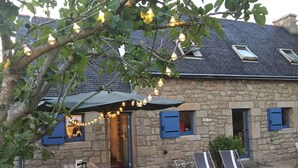Ein Steinhäuschen mit Terrasse, Sitzgelegenheiten und Lichterkette.