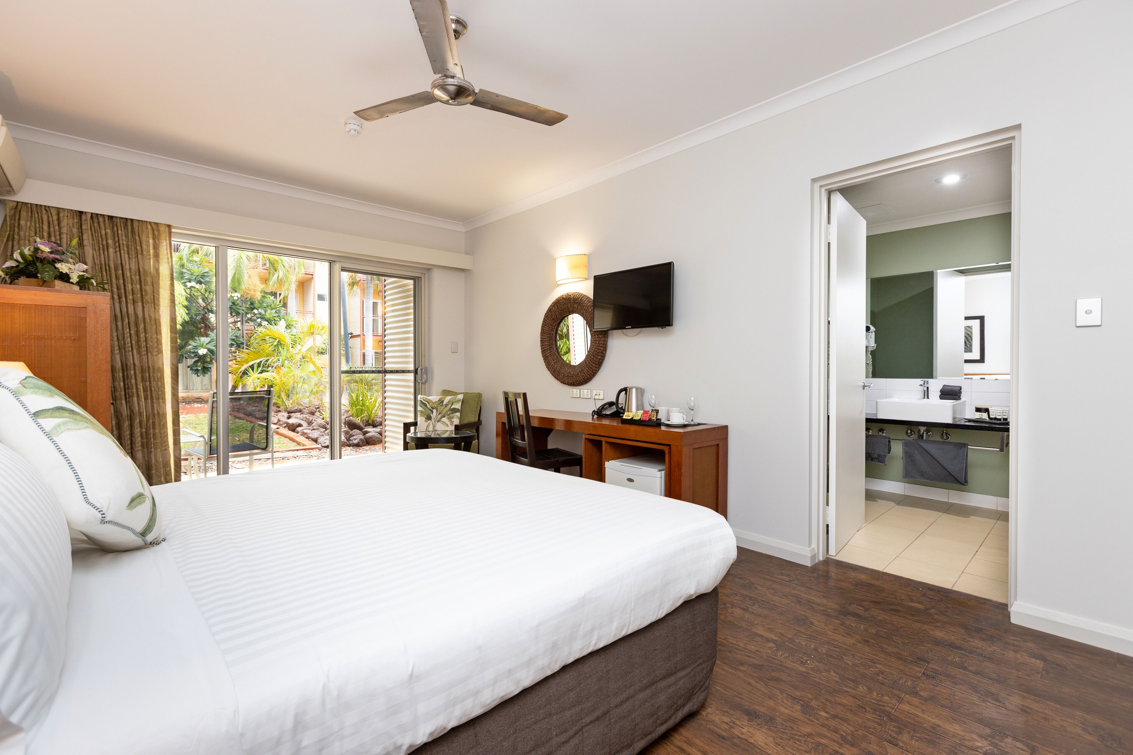 A hotel room with a large bed, a desk, a television, and a view of the outdoors.