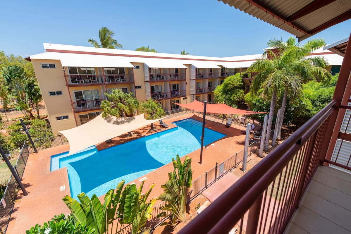 Ein Hotel mit Schwimmbad, mehreren Balkonen und tropischer Bepflanzung.