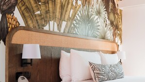 A hotel room with a large bed, a nightstand, a wall-mounted lamp, and a tropical-themed mural. - The Continental Hotel Broome (Broome)