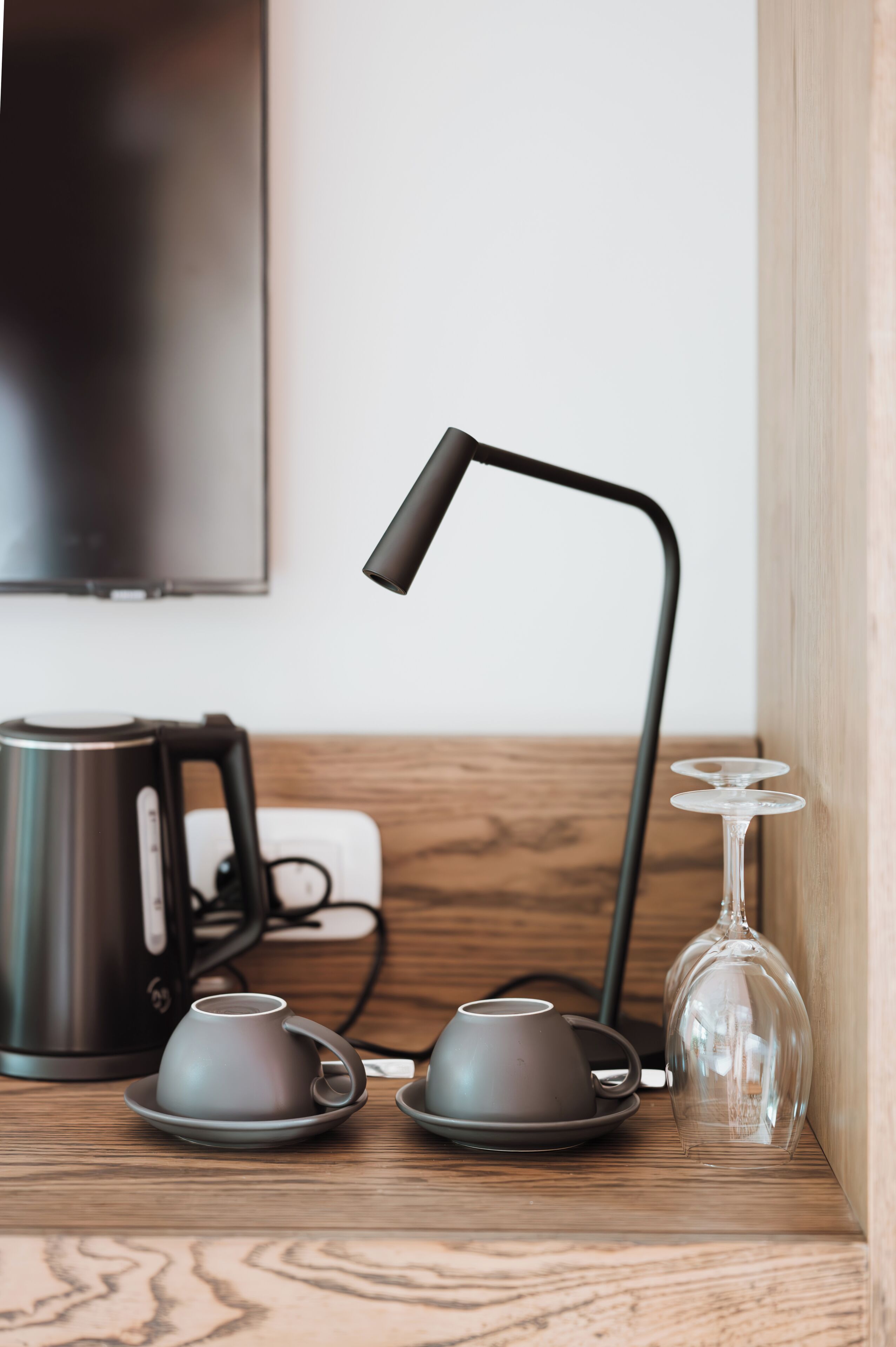 Une étagère en bois avec une bouilloire, deux tasses, un verre et une lampe.