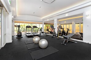 Un gimnasio con cintas de correr, elípticas y pelotas de ejercicio.