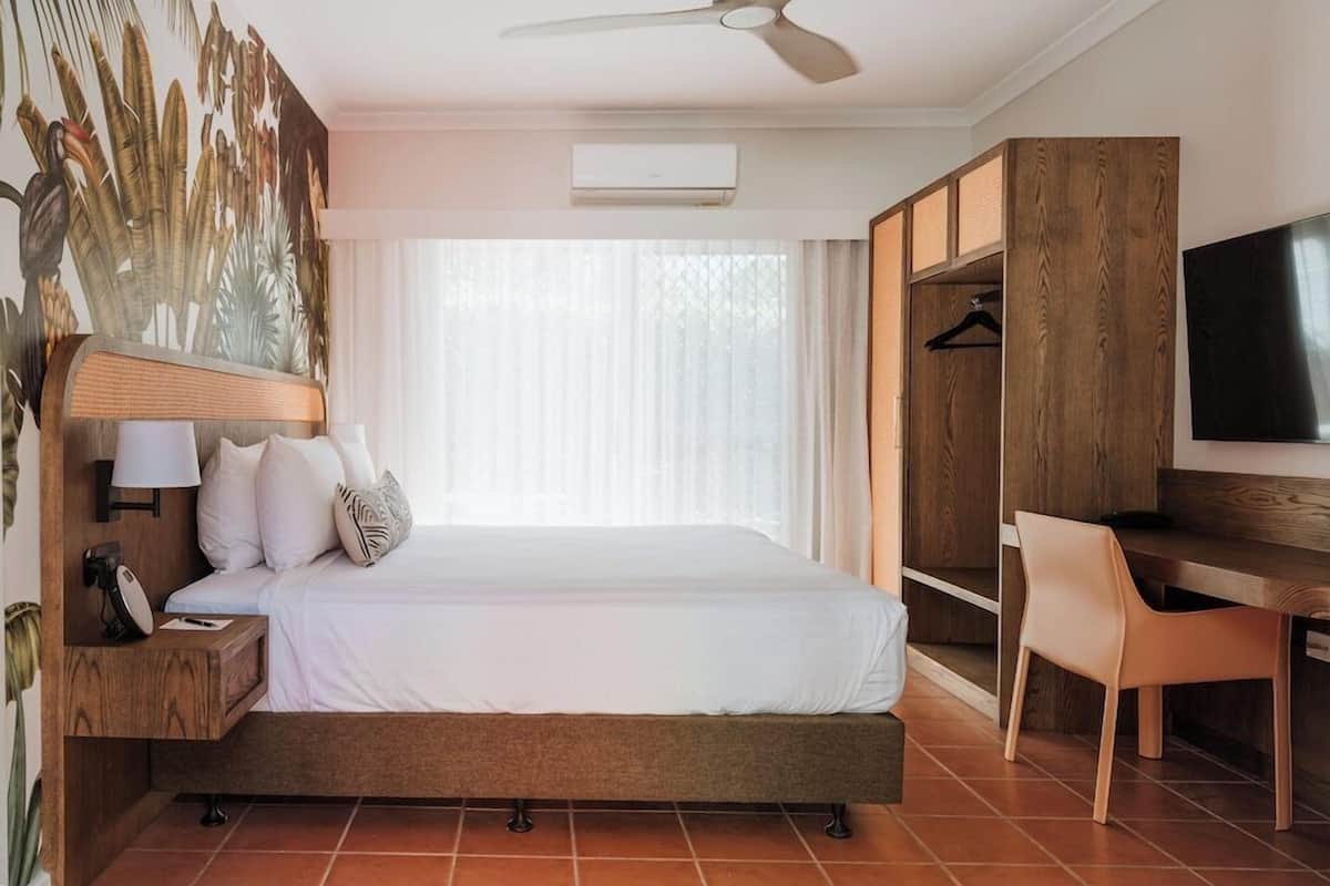 Ein Hotelzimmer mit Bett, Schreibtisch, Stuhl, Fernseher und Kleiderschrank.