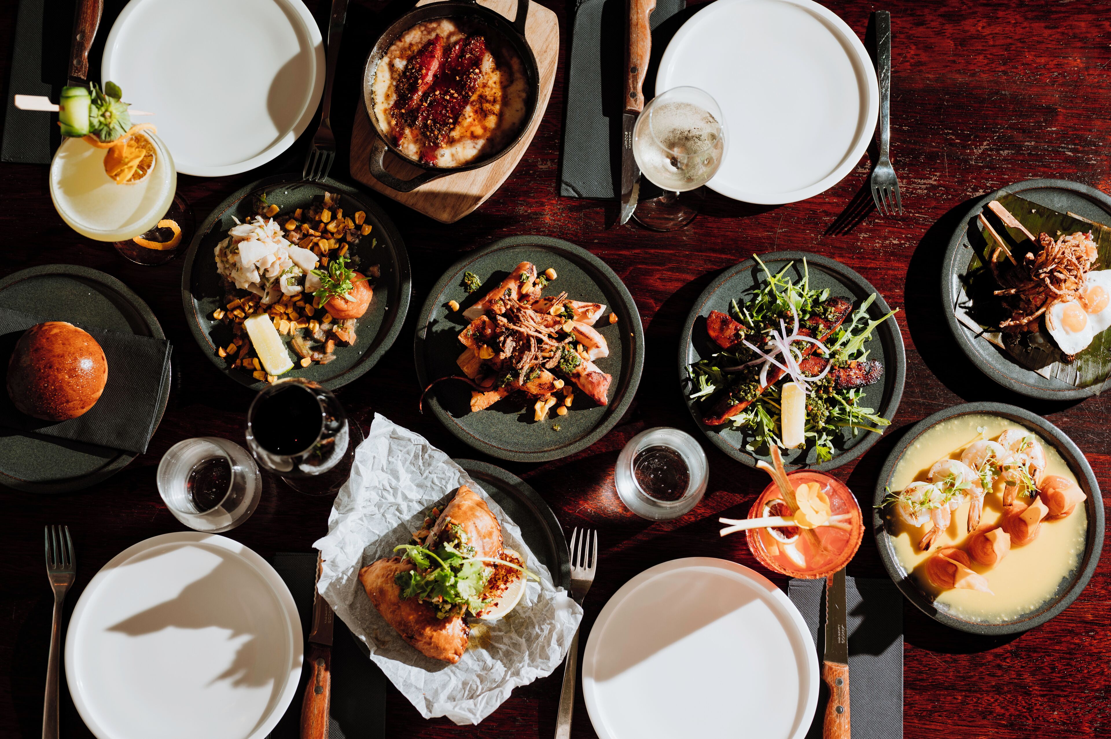 Une table à manger dressée avec différents plats, notamment des fruits de mer, des salades et du pain, prêts à être servis.