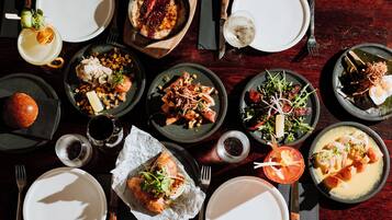 Une table à manger dressée avec différents plats, notamment des fruits de mer, des salades et du pain, prêts à être servis.