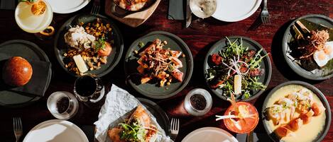 Une table à manger dressée avec différents plats, notamment des fruits de mer, des salades et du pain, prêts à être servis.