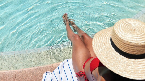 A person relaxing by a pool with clear water, wearing a straw hat and striped clothing. - The Continental Hotel Broome (Broome)