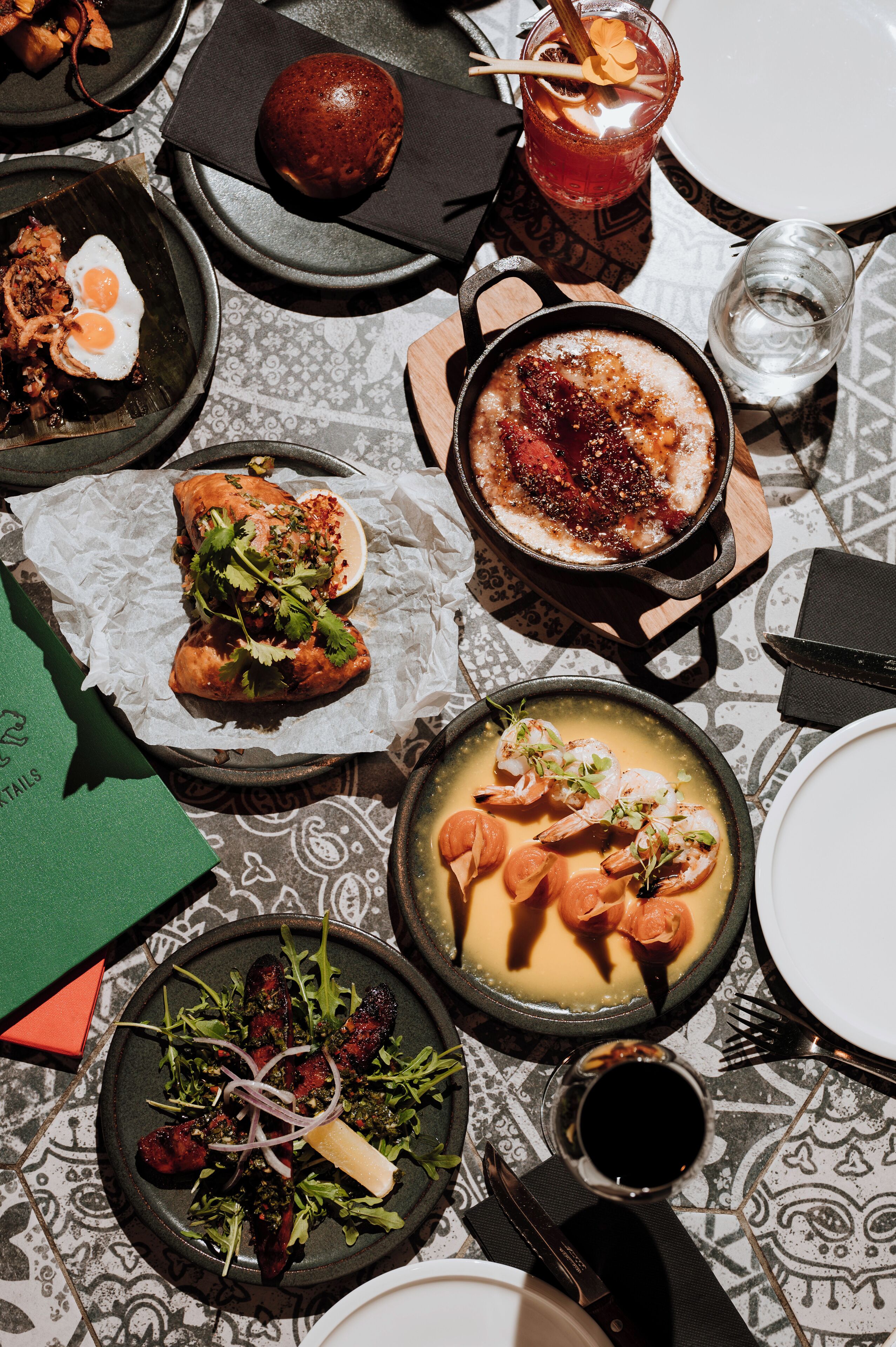 A table set with various dishes including a bowl of soup, a plate of salad, and a pan of food, suggesting a meal setting.