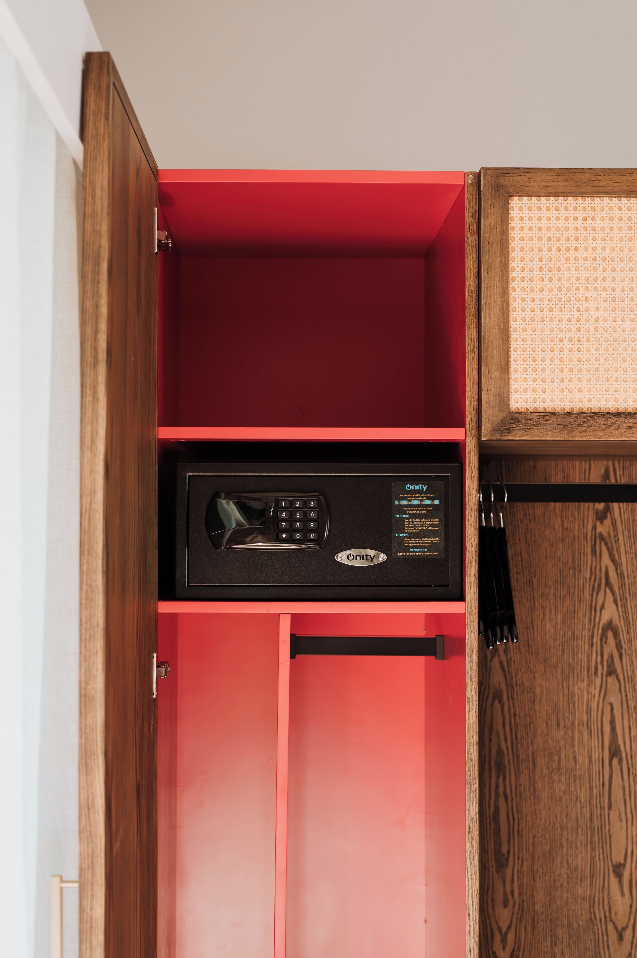 Ein roter Schrank mit einem schwarzen Gerät im Inneren, möglicherweise ein Tresor oder ein abschließbarer Stauraum.