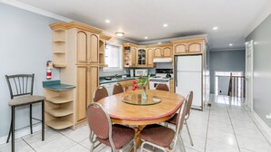 A modern kitchen with a dining area, featuring a round glass table, wooden cabinets, and a built-in microwave.