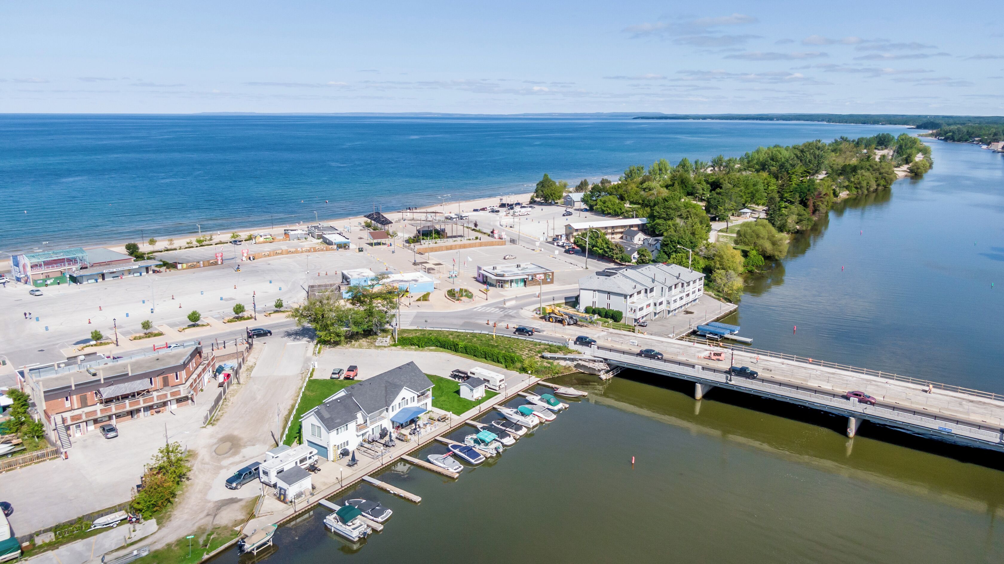 An aerial view of a coastal town with a marina, a bridge, and a beach.