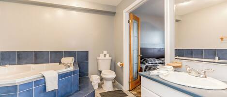 Een badkamer met een bad, toilet, wastafel en spiegel.