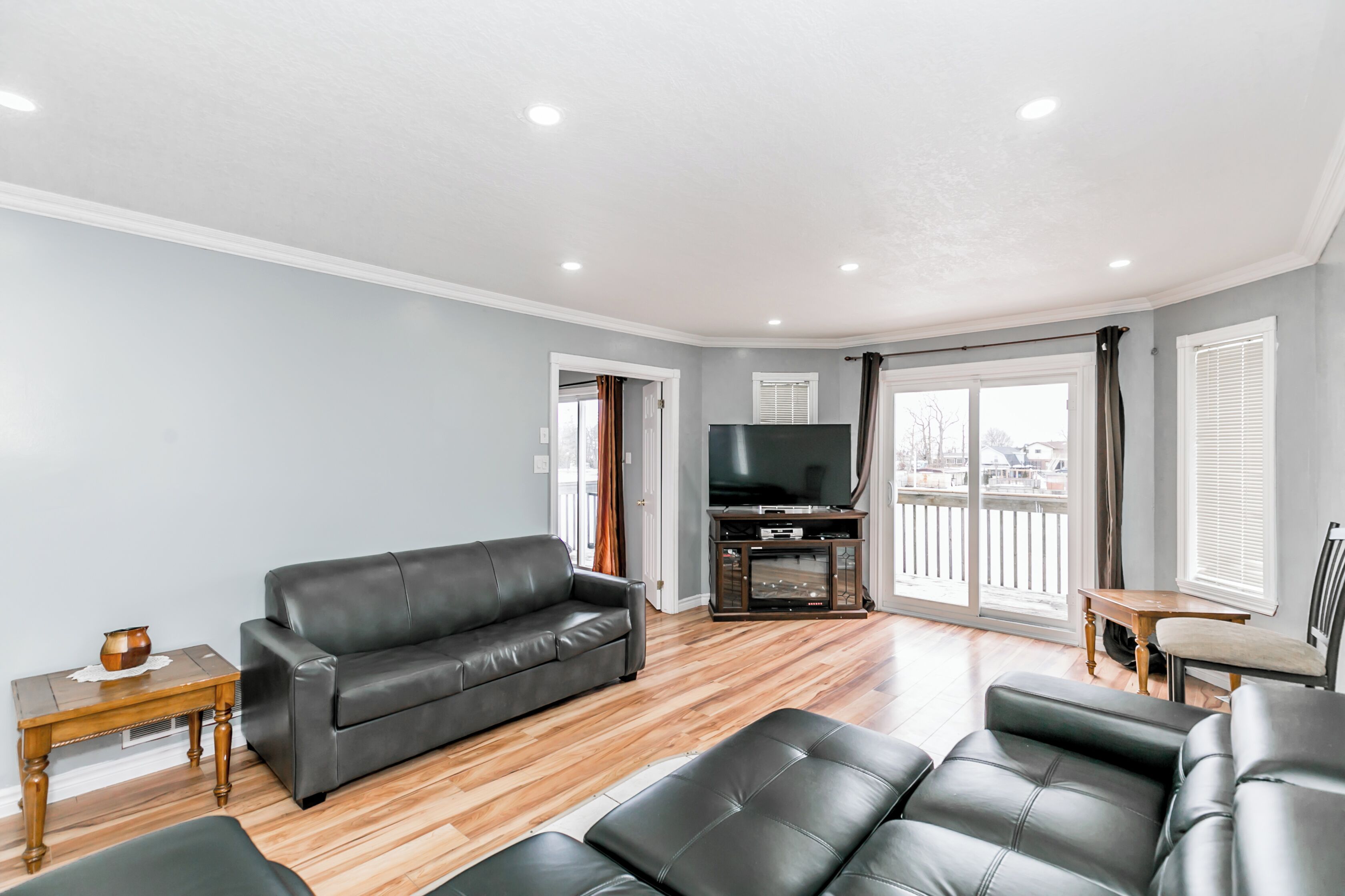 A living room with a sofa, a television, and a balcony view.