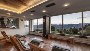 Un cuarto de spa con sillas de madera, un ventanal con vistas a la montaña e iluminación empotrada en el techo.
