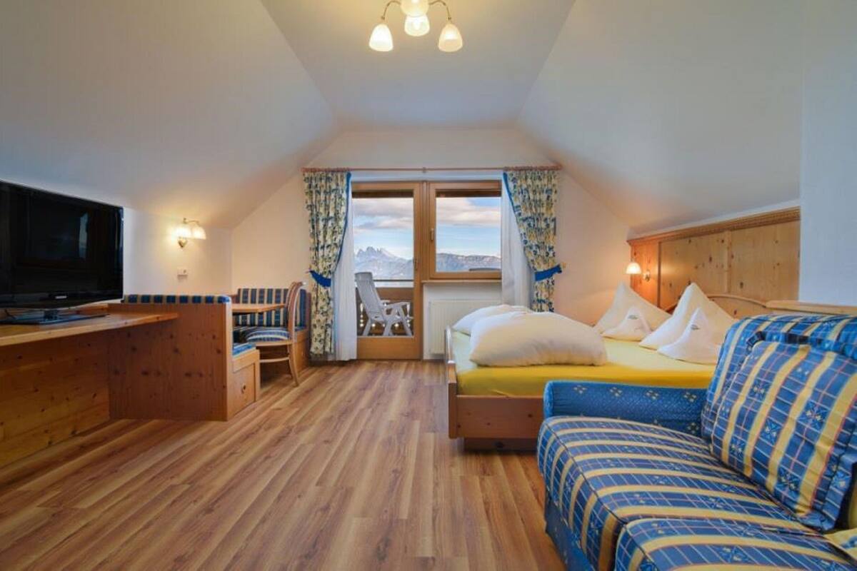 Una habitación acogedora con cama, sofá, televisor y escritorio de madera.