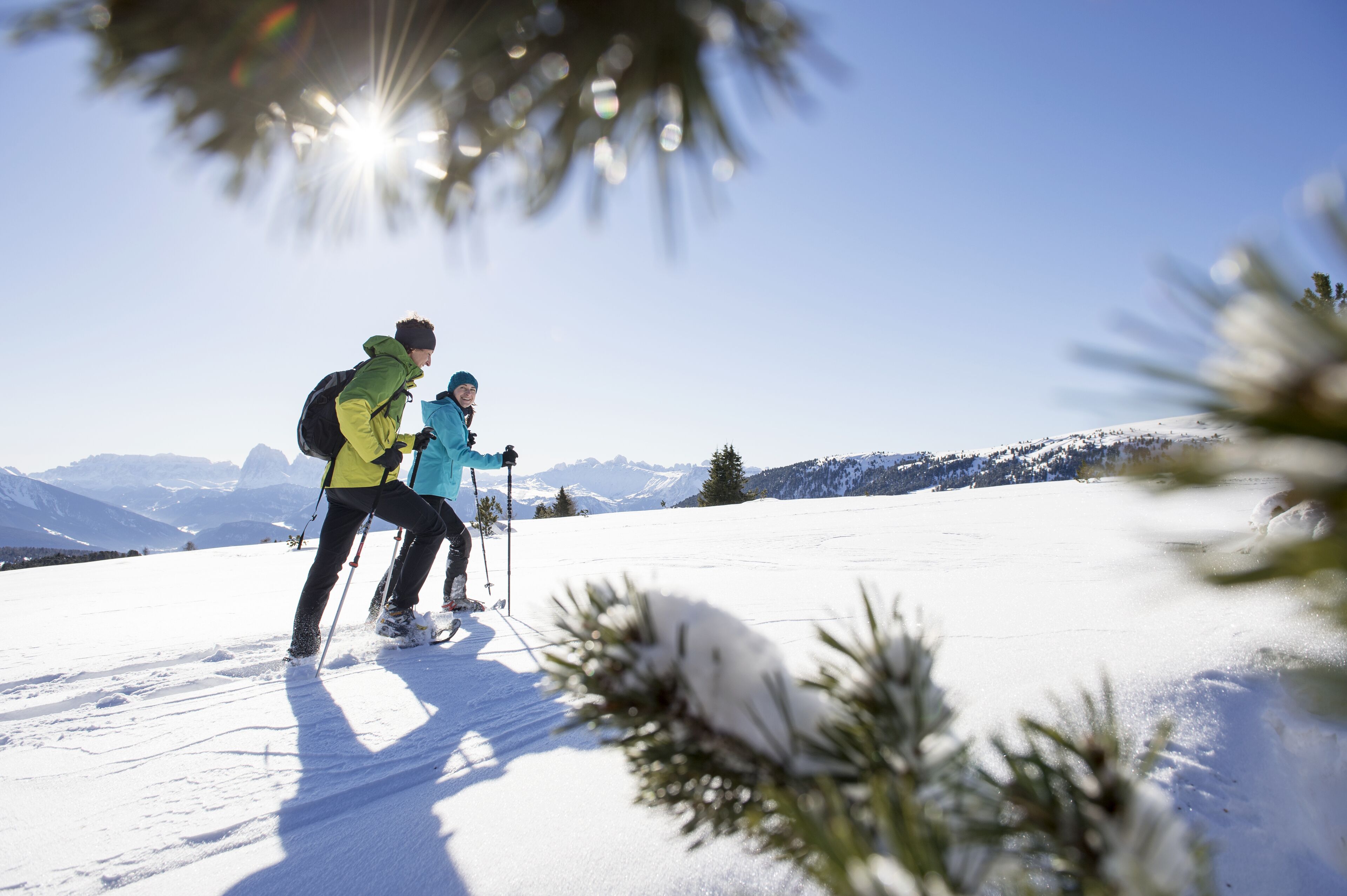 Two people skiing on a snowy mountain with a clear sky.