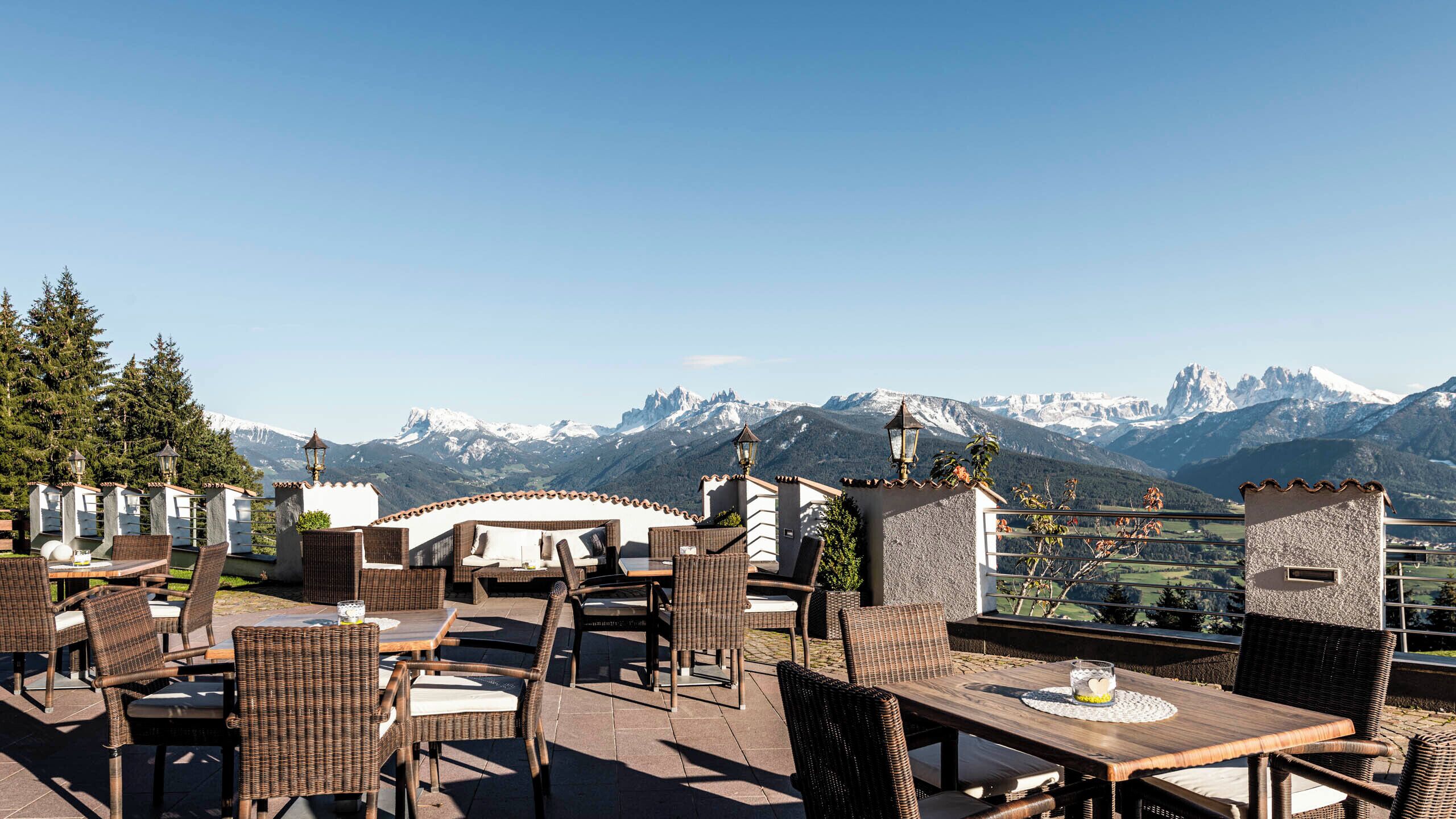 An outdoor seating area with wicker furniture and a view of snow-capped mountains.