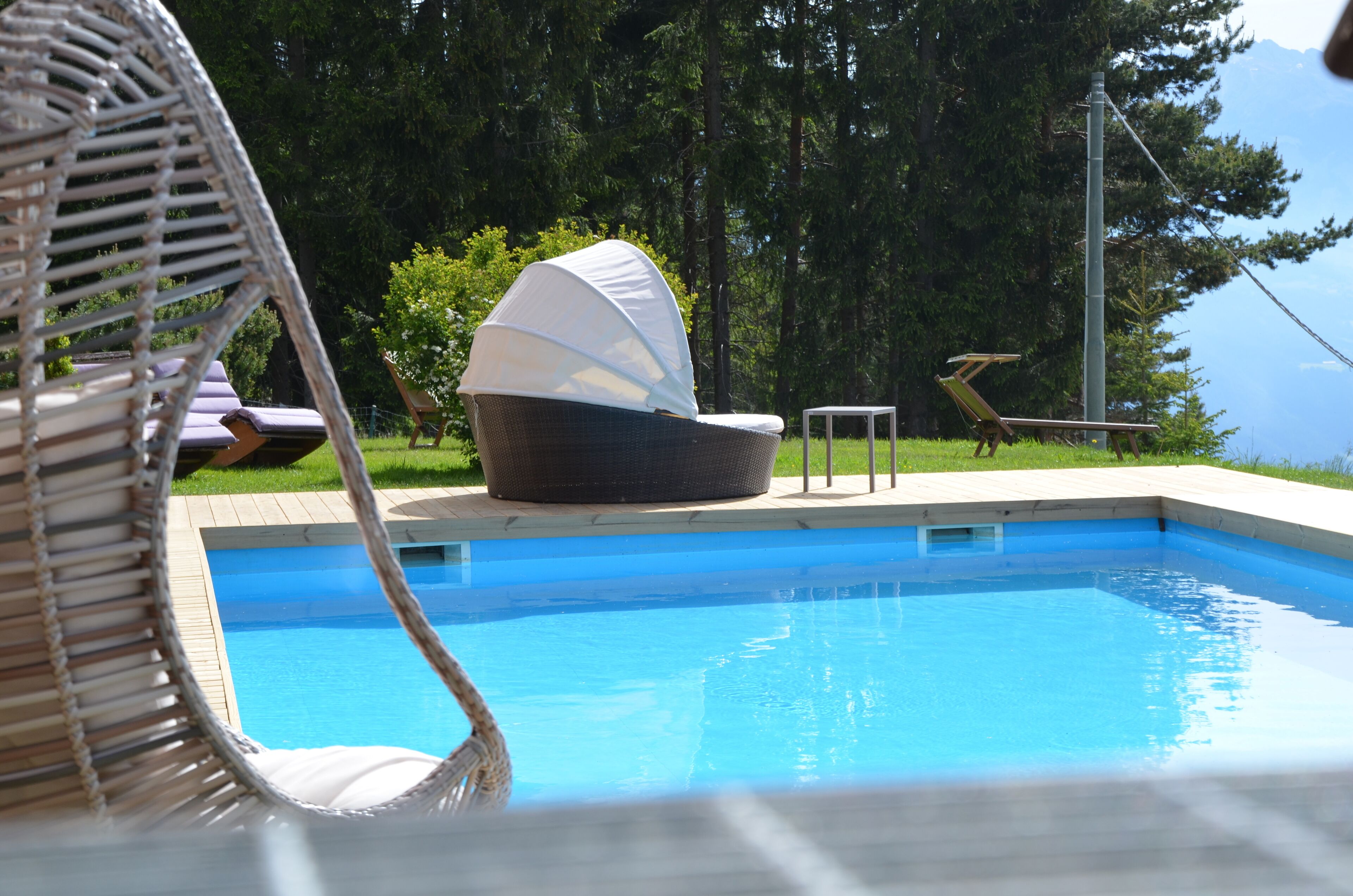 Ein Schwimmbecken mit Liegestühlen und einer überdachten Sitzgruppe.