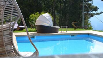 Ein Schwimmbecken mit Liegestühlen und einer überdachten Sitzgruppe.