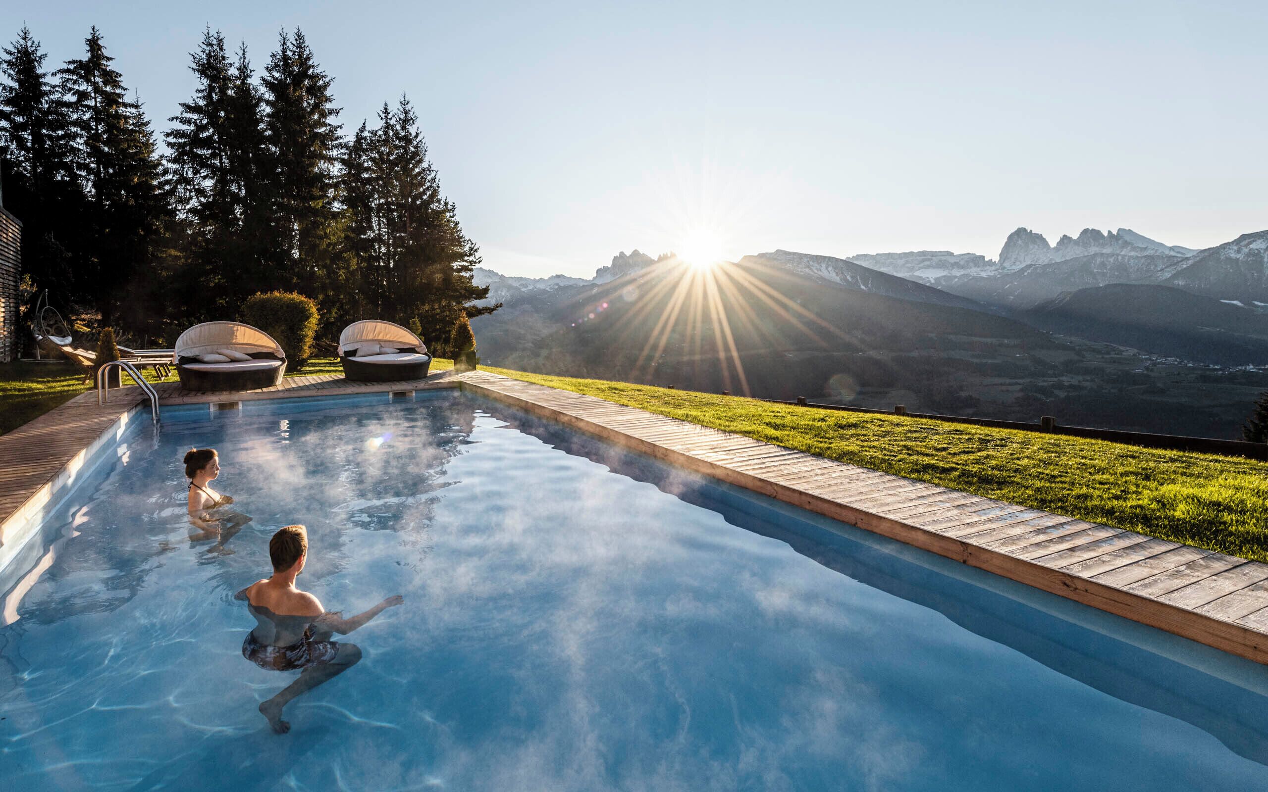 A swimming pool with two lounge chairs and a view of mountains.