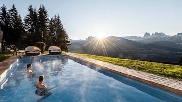 A swimming pool with two lounge chairs and a view of mountains.