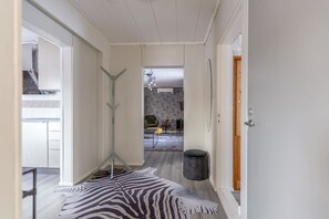 A hallway with a zebra-patterned rug, a standing lamp, and a door leading to another room. - Kuukkeli Ivalo Arctic House (Inari)