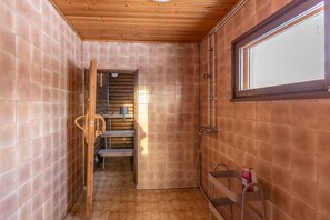 A bathroom with wooden walls, a window, and a shower area. - Kuukkeli Ivalo Arctic House (Inari)