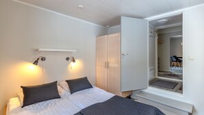 Un dormitorio con cama, lámparas de noche, armario y espejo.